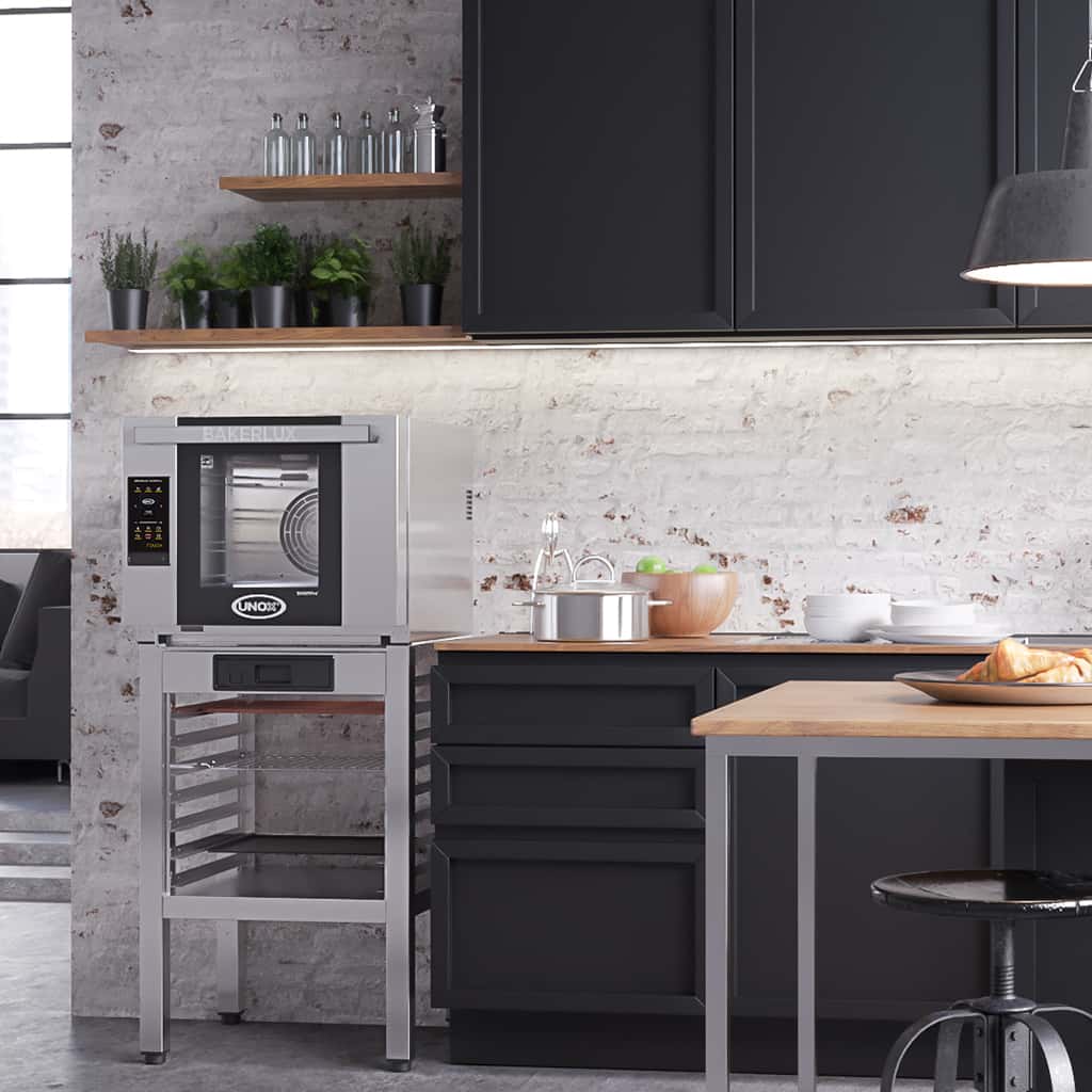 Modern home kitchen with white exposed brick wall, an Unox bakerlux oven sits on a stand next to the kitchen counter.