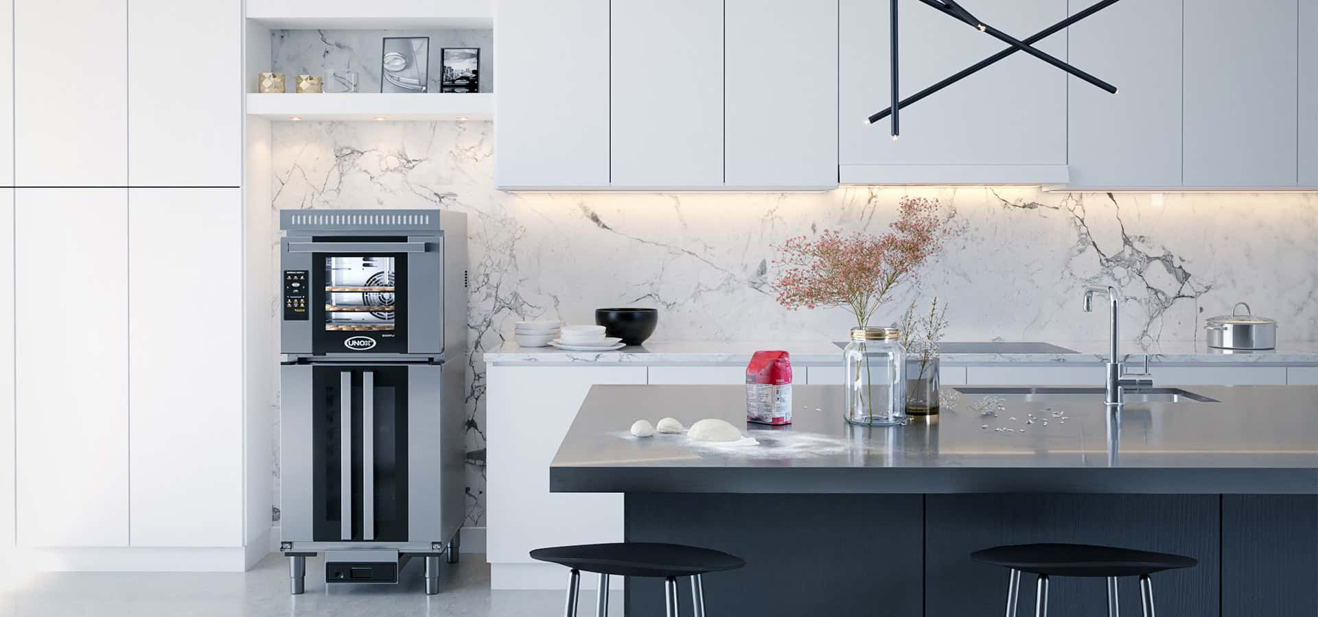 Modern white home kitchen, an Unox oven on top of a prover sits next to the kitchen counter, dough and flour are on the kitchen table.