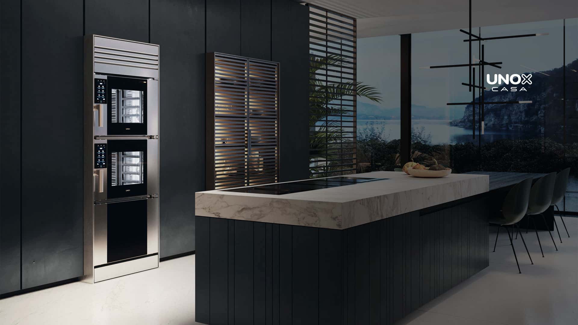 Cucina di lusso con grande piano in marmo e vista sull’oceano dalla finestra, con forno combinato a incasso, impilato su un altro.