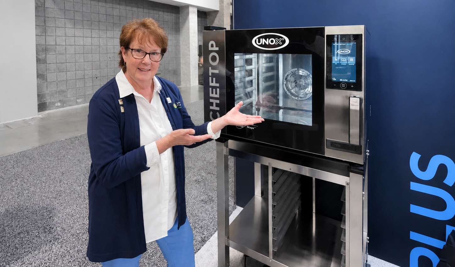 School nutrition consultant Carrie Frank standing next to a commercial combi oven used in K-12 school kitchens