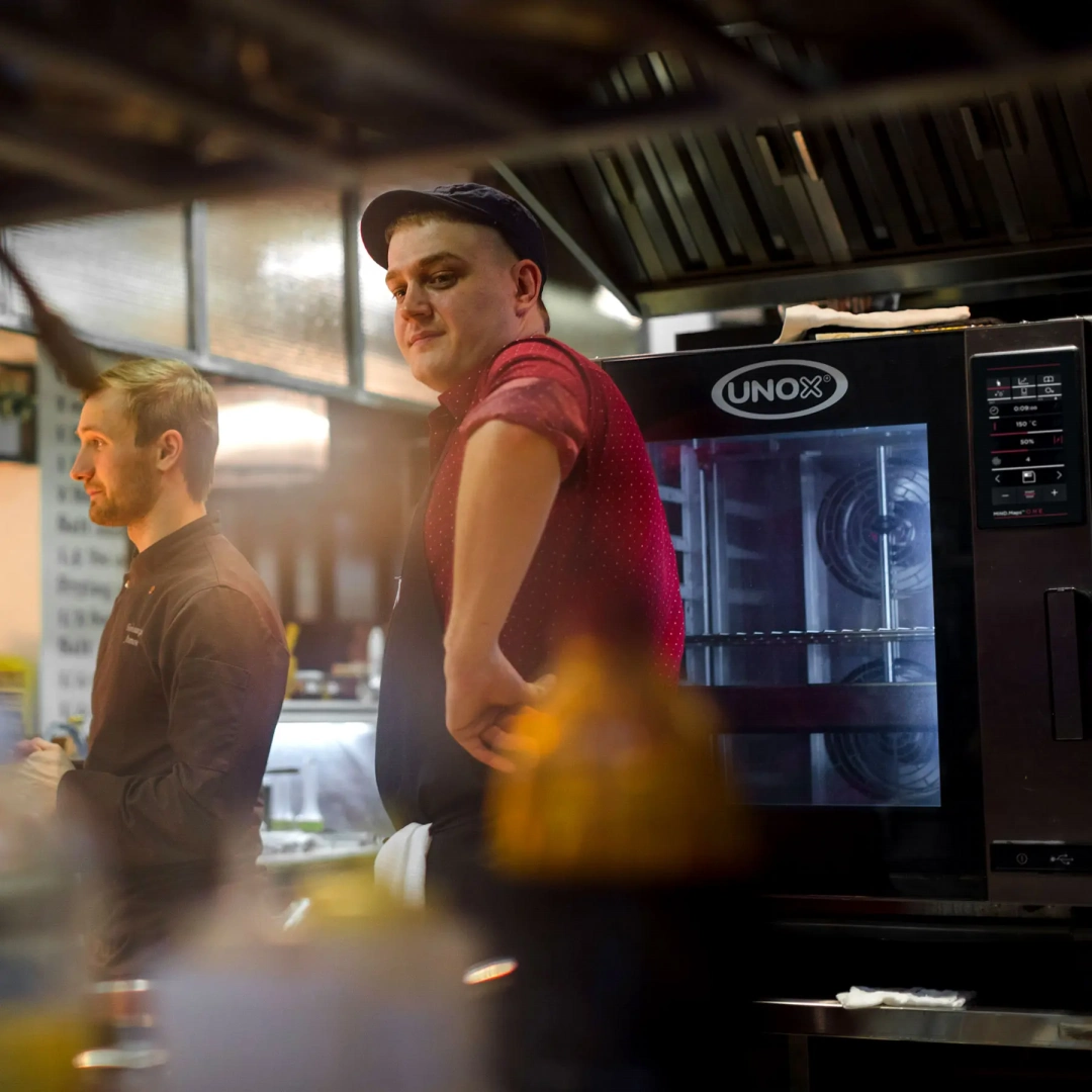 Man wearing an apron stood in front of an Unox combi oven.