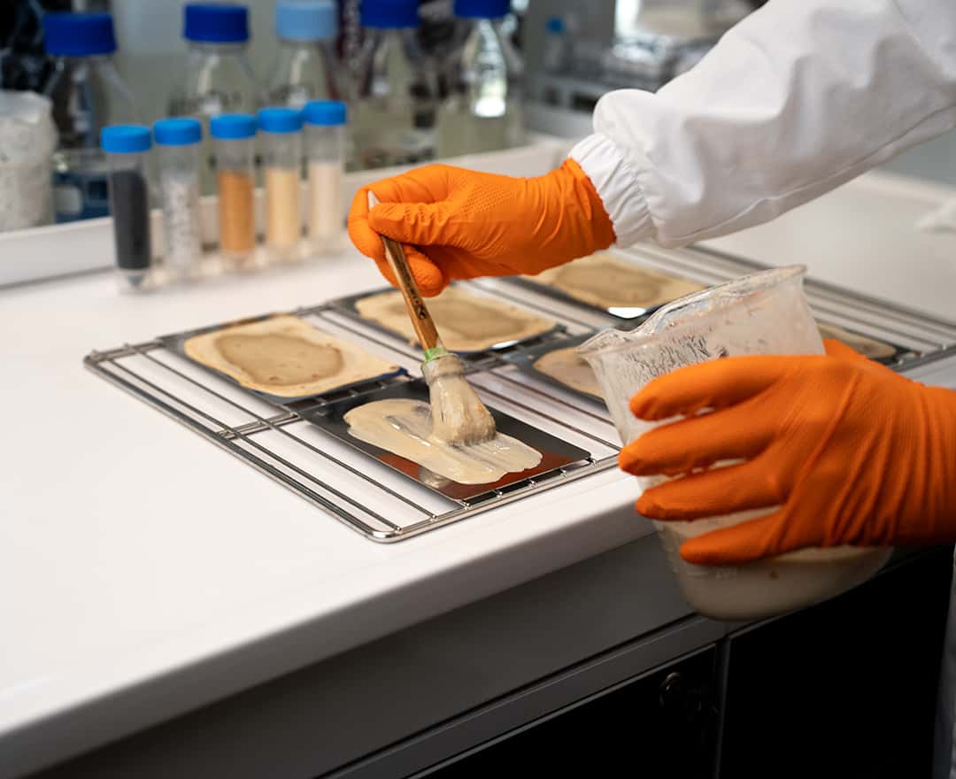 chemist applying a soil compound to a stainless steel sample to test cleaning effectiveness