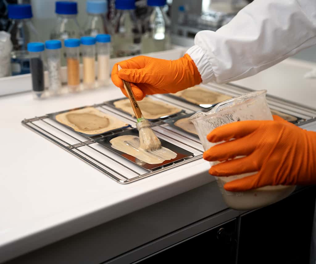 chemist applying a soil compound to a stainless steel sample to test cleaning effectiveness