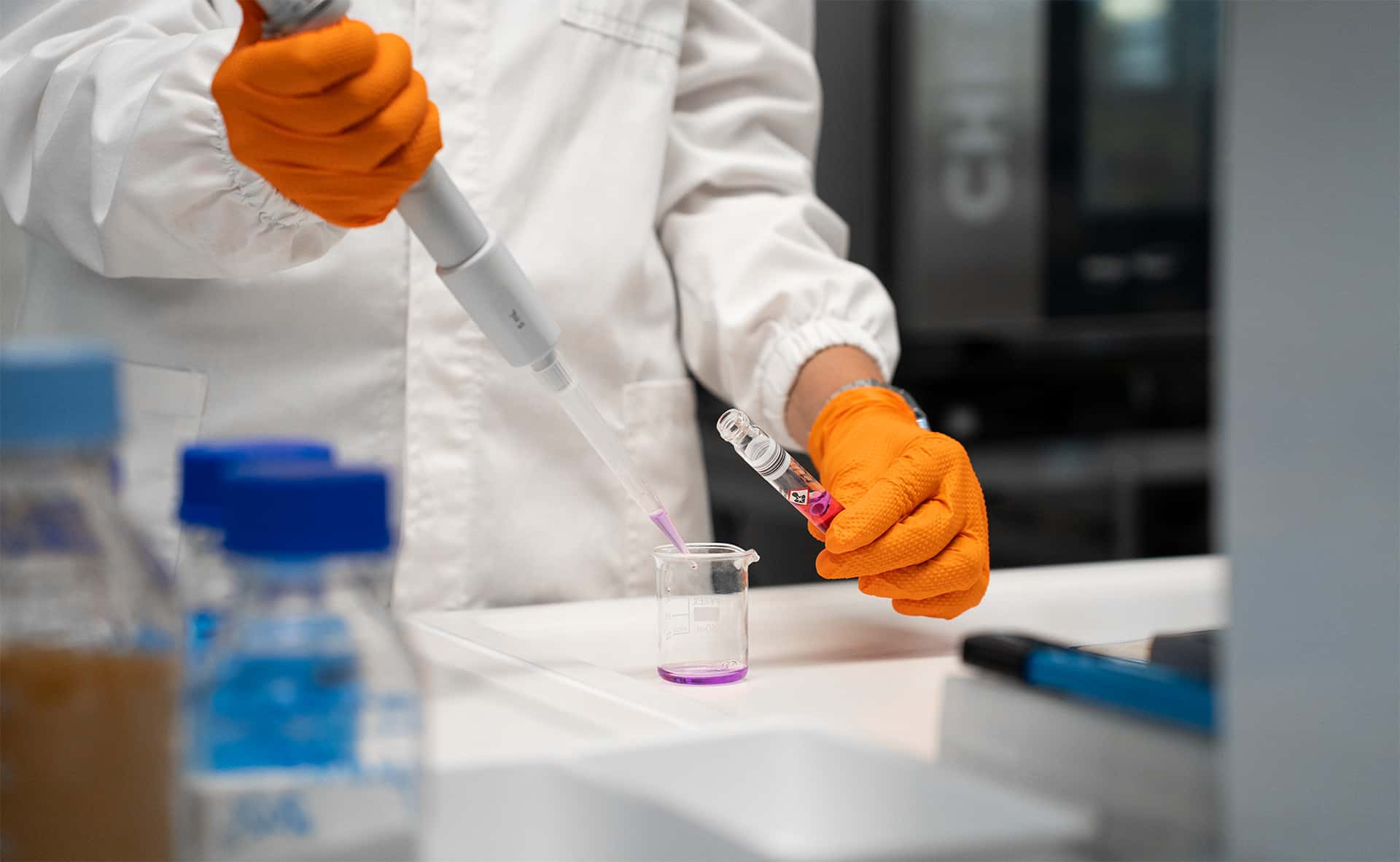 chemist pouring liquid into a beaker on a lab bench