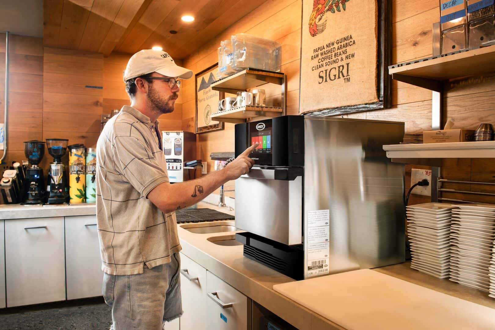 Un camarero en un restaurante de servicio rápido utiliza un horno rápido Unox, interactuando con su panel táctil.