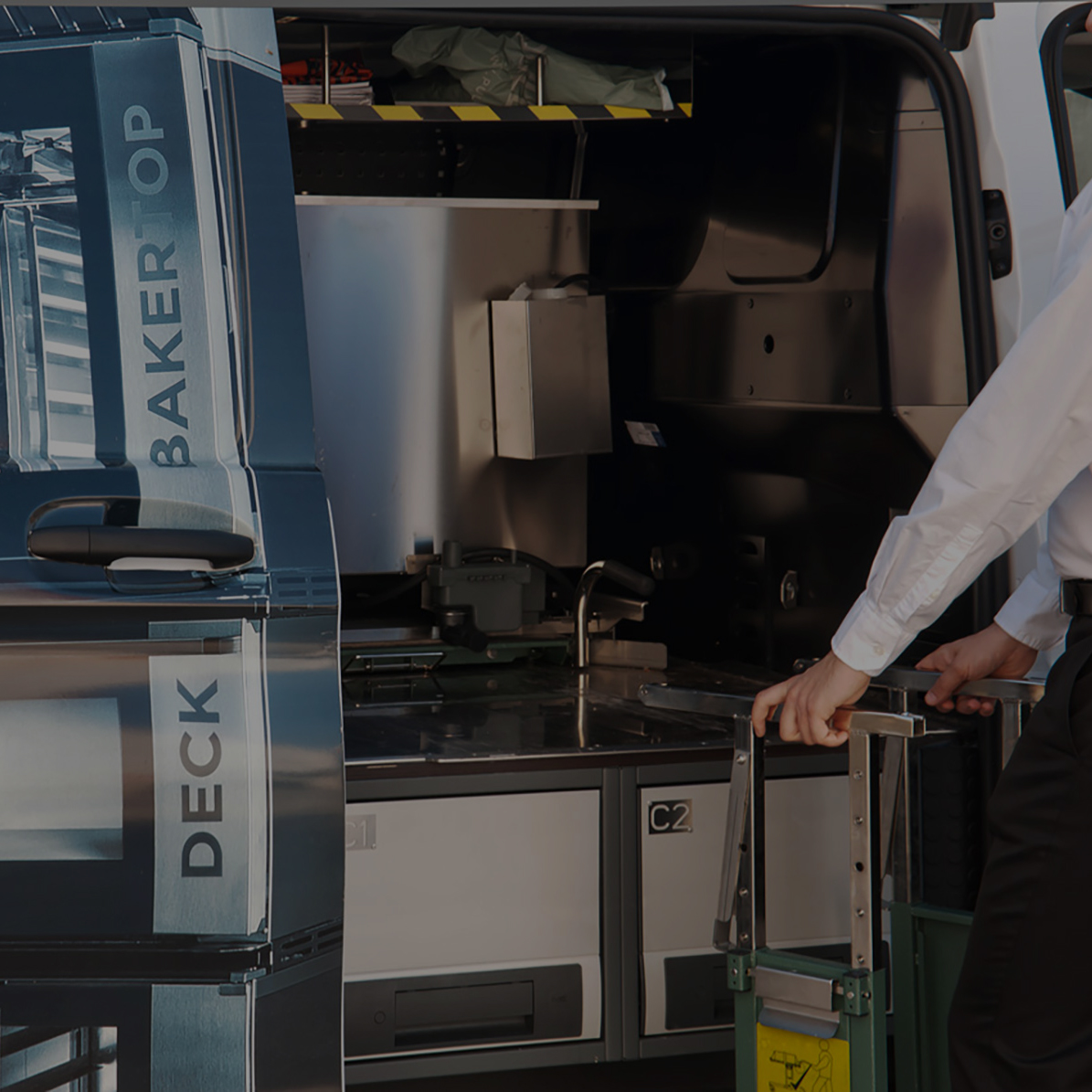 Man moving a loading tool towards the back of a van, Unox ovens can be seen on the graphics on the back door of the van.